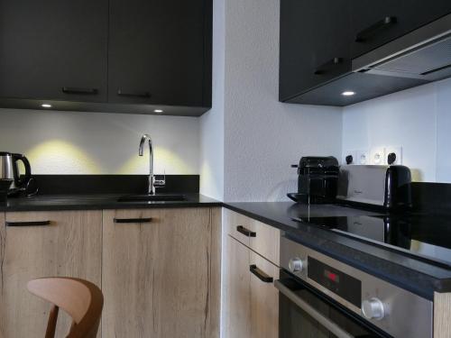 - une cuisine avec des comptoirs noirs et un évier dans l'établissement Confort moderne aux 2 Alpes : Bel appart 45 m², 6 pers, résidence NEIGE et SOLEIL, proche des pistes - FR-1-546-37, à Les Deux Alpes