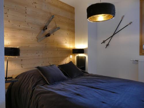 - une chambre avec un lit et un mur en bois dans l'établissement Confort moderne aux 2 Alpes : Bel appart 45 m², 6 pers, résidence NEIGE et SOLEIL, proche des pistes - FR-1-546-37, à Les Deux Alpes