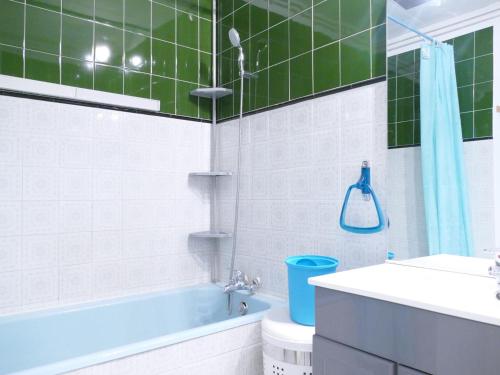 La salle de bains est pourvue d'une baignoire bleue et de carrelage vert. dans l'établissement Joli studio centre station avec lits superposés - FR-1-546-45, à Les Deux Alpes