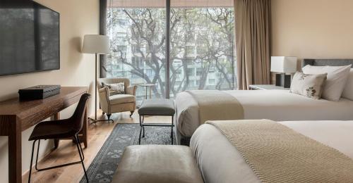 a hotel room with two beds and a desk and a window at Hotel Montevideo - Leading Hotels of the World in Montevideo