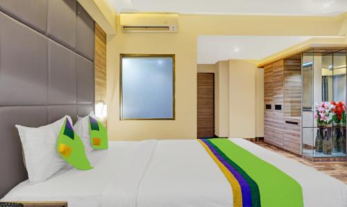 a bedroom with a large white bed with green pillows at Treebo Classic Grande, Camp in Pune