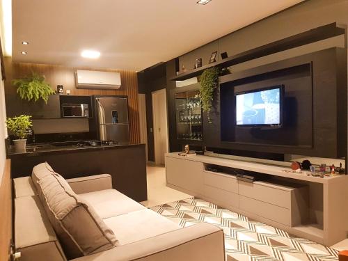 uma sala de estar com um sofá e uma televisão de ecrã plano em Apartamento ao lado da Vila Germânica em Blumenau