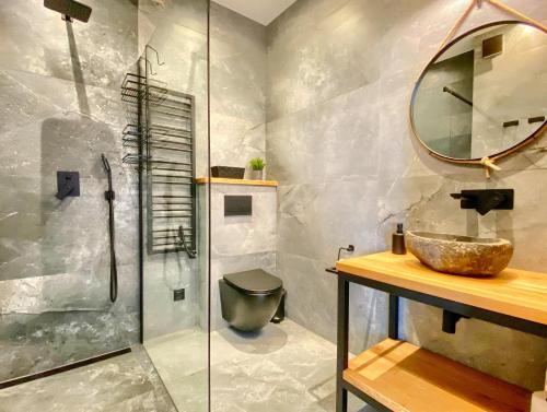 a bathroom with a sink and a glass shower at Domki Tatrzańska Panorama z jacuzzi in Ząb