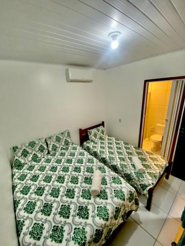 een slaapkamer met een bed met een groen en wit dekbed bij A casa miracles in São Miguel dos Milagres