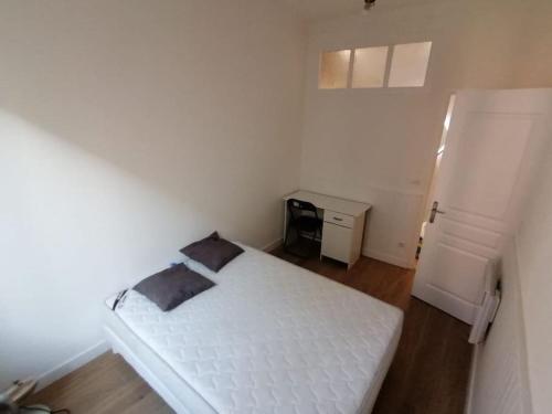 a bedroom with a white bed and a refrigerator at Joli T2 rénové à 100m de Monaco in Beausoleil