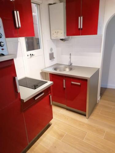 a kitchen with red cabinets and a sink at Joli T2 rénové à 100m de Monaco in Beausoleil