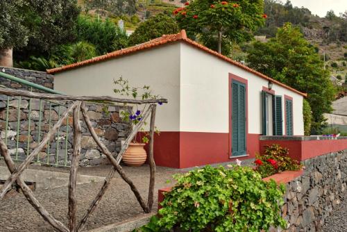 une petite maison sur une colline avec un mur en pierre dans l'établissement Cicas Studio, a Home in Madeira, à Arco da Calheta