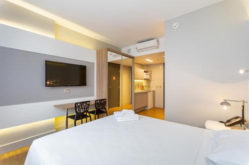 a hotel room with a bed and a tv on the wall at Studio Premium Batel - HSB002 in Curitiba