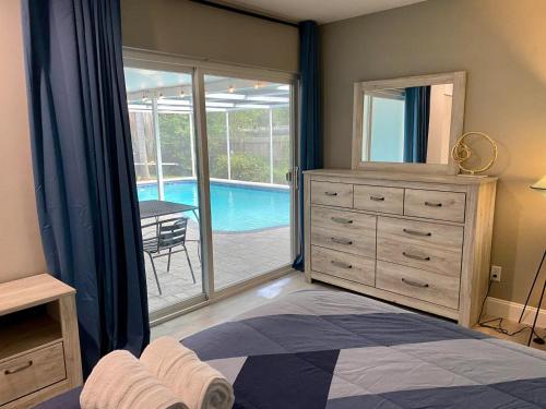 a bedroom with a dresser and a large window with a pool at Spacious 5 bedrooms 3 bathrooms Family-Friendly Home With Heated salt Pool in Clearwater