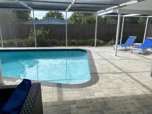 a swimming pool with two blue chairs and an umbrella at Spacious 5 bedrooms 3 bathrooms Family-Friendly Home With Heated salt Pool in Clearwater