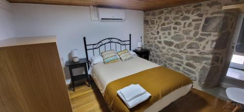a bedroom with a bed and a stone wall at Casa Cerralleiro. Casa vacacional en Parada de Sil. Ribeira Sacra. in Parada del Sil