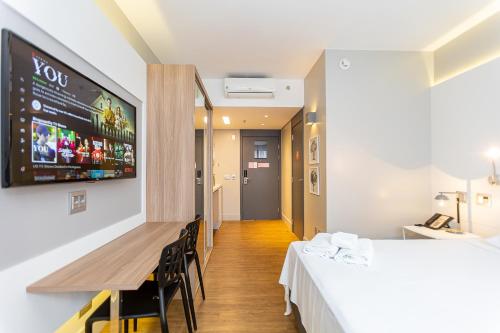 a room with two beds and a table and a tv at Studio Premium Batel - HSB002 in Curitiba