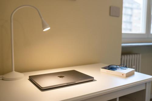 a laptop on a desk with a lamp and a box at Appartamenti Vista Mole, Centro a 15 min - Luxury Suites & fast WiFi in Turin