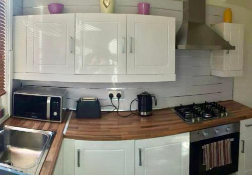 a kitchen with white cabinets and a counter with a microwave at Vinery House in Leeds