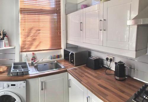 a kitchen with white cabinets and a sink at Vinery House in Leeds