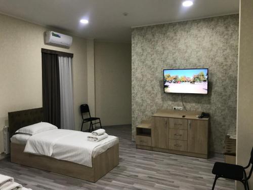 a bedroom with a bed and a tv on a wall at MAZZA Hotel in Tashkent