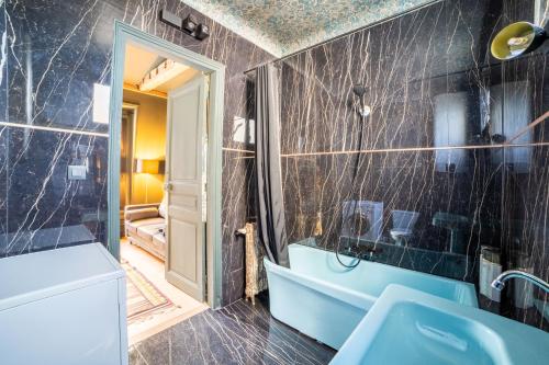 ein Badezimmer mit einer blauen Badewanne und einem Waschbecken in der Unterkunft Place Vendôme Luxe 60 SQM Bail mobilité in Paris