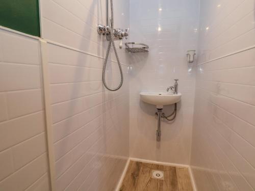 a white bathroom with a sink and a shower at The Suffolk in St Asaph