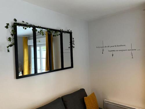 a mirror on a wall with a couch in a room at Urban Home - 4 pers - Netflix in Eysines