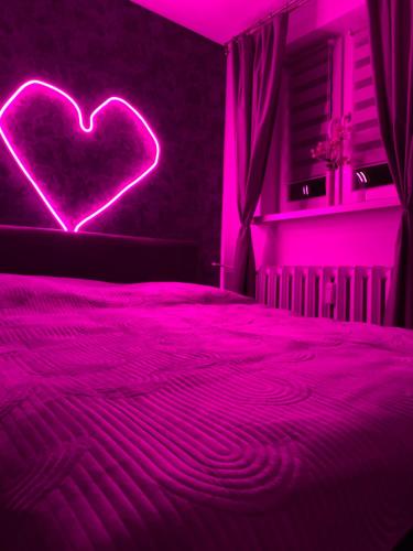 a bedroom with a heart neon sign on a bed at New Classic 30m. in Piła