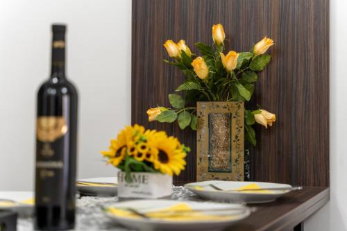 a table with a vase of yellow flowers and a bottle of wine at Durmitor 41, kompleks Titova Vila in Palisad