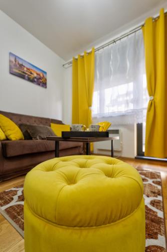 a yellow ottoman in the middle of a living room at Durmitor 41, kompleks Titova Vila in Palisad