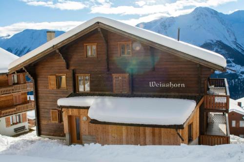ein Blockhaus im Schnee mit Bergen im Hintergrund in der Unterkunft Chalet Weisshorn 1 in Bettmeralp