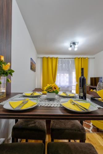 a dining room table with yellow napkins and yellow curtains at Durmitor 41, kompleks Titova Vila in Palisad