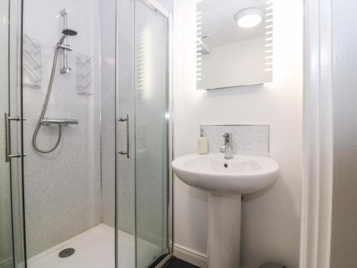 a white bathroom with a sink and a shower at Kilmuir Cottage in Tomintoul