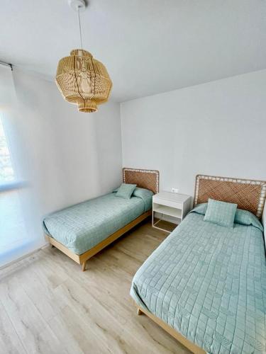 a bedroom with two beds and a chandelier at Marina Real 82 by homeprive in Denia