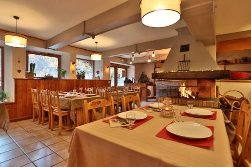 una sala da pranzo con tavoli, sedie e camino di Hôtel Restaurant Gîtes Les 5 Saisons a Freissinieres