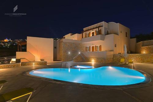una gran piscina frente a una casa por la noche en Moonlight Apartments, en Fira