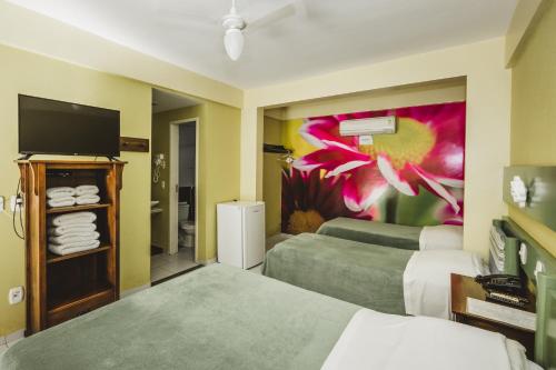 a hotel room with two beds and a tv at Hotel Pousada Vovô Zinho in Siqueira Campos