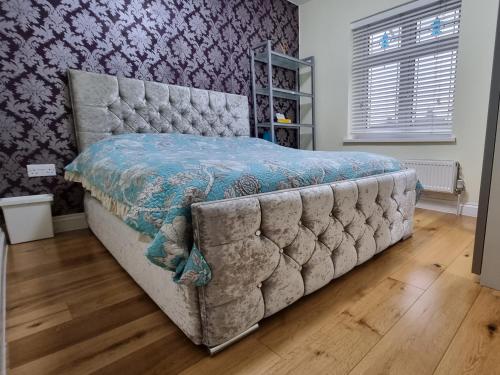 a bedroom with a bed with a tufted headboard at 2 ROOMS ANNEX (TV+WiFi) in Chigwell