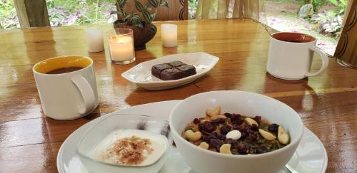 a table with a bowl of food and two cups of coffee at Wildlife Lodge Cahuita in Cahuita
