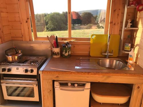 a kitchen with a sink and a stove and a window at Gwynfyd Bell Tent in Abergavenny
