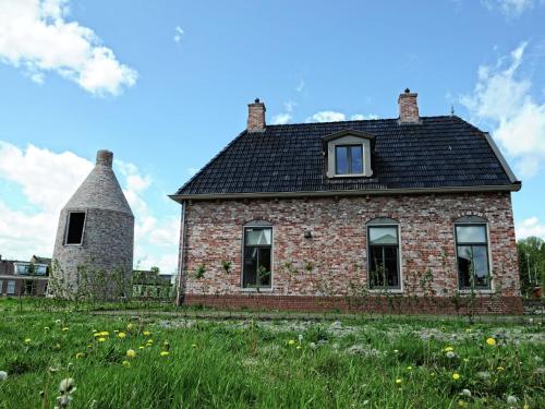 ZoutkampにあるFisherman s house near the Lauwersmeerの風車のある古いレンガ造りの家