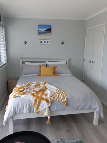 1 dormitorio con cama blanca y almohadas de color naranja en Seascape Hideaway Pohara en Pohara