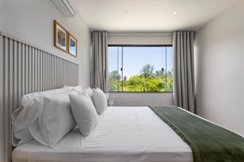 a bedroom with a large white bed with a window at Charme na Barra da Tijuca - Bela Vista - AM203 Z10 in Rio de Janeiro