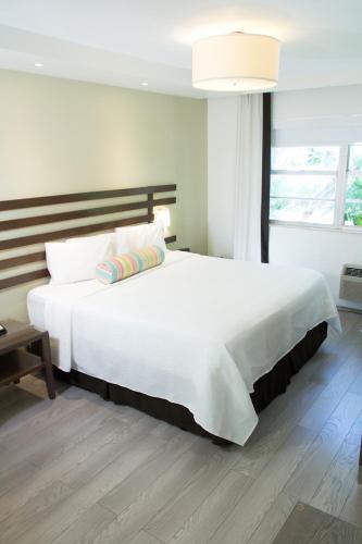 a large white bed in a room with a window at Dorchester Hotel & Suites in Miami Beach