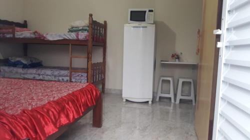 a room with a refrigerator and a bed in a room at Cantinho da Gigi in Peruíbe