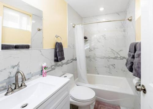 een witte badkamer met een wastafel, een toilet en een bad bij 233/1-Boston family-friendly first floor apartment in Boston