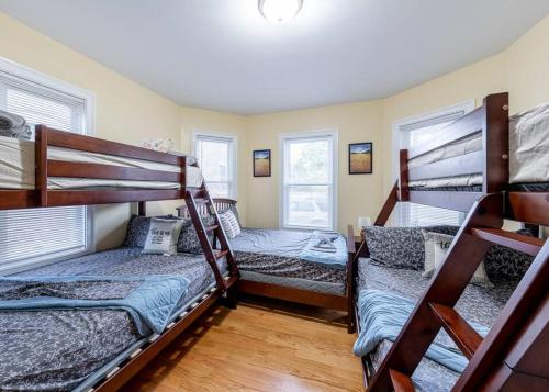 een kamer met 3 stapelbedden en 2 ramen bij 233/1-Boston family-friendly first floor apartment in Boston