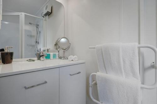 a white bathroom with a sink and a towel rack at Mission Bay Secret Garden Hideaway - Netflix WIFI in Auckland