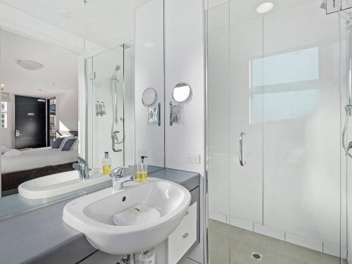 y baño blanco con lavabo y ducha. en Marina Gem - Lakefront 3 Bedroom Apartment, en Queenstown