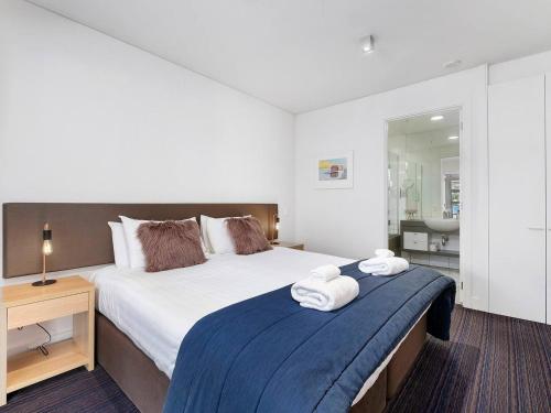 a bedroom with a large bed with towels on it at Marina Gem - Lakefront 3 Bedroom Apartment in Queenstown