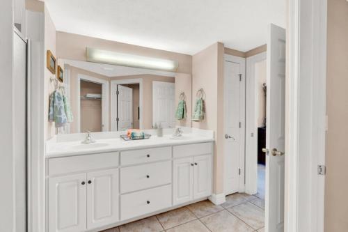 a bathroom with two sinks and a large mirror at Treasure Island 707 - Gulf front, sunset views, heated resort pool & hot tub! in Panama City Beach