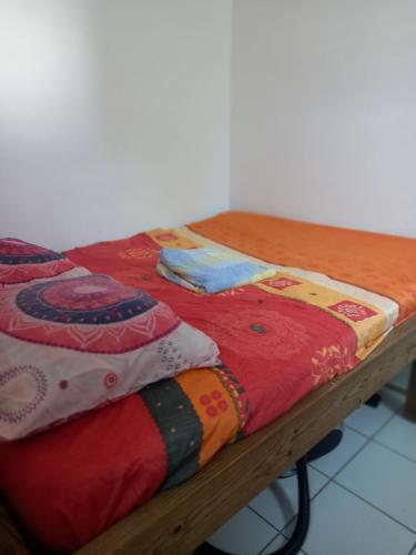 a wooden table with a bed with colorful blankets at Niky house in Fort-de-France