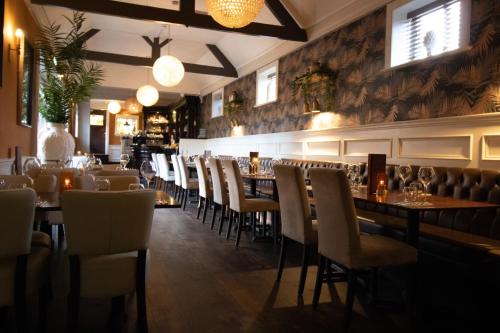 a restaurant with tables and chairs in a room at The Wheatsheaf Pub, Kitchen & Rooms in Bingham
