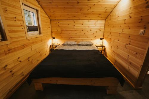 ein Schlafzimmer mit einem Bett in einer Holzhütte in der Unterkunft Domki Rower-Narty-Leżak - całoroczne, niezależne, taras, grill, duży teren, blisko las, trasy rowerowe single-track, piesze wędrówki, narty in Świeradów-Zdrój